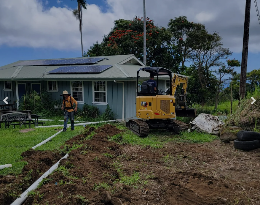 PBC crew trenching plumbing lines with CAT excavator on Hawaii property
