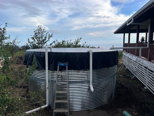 Pioneer water catchment tank installation at a Captain Cook, Hawaii property with Pacific Ocean horizon