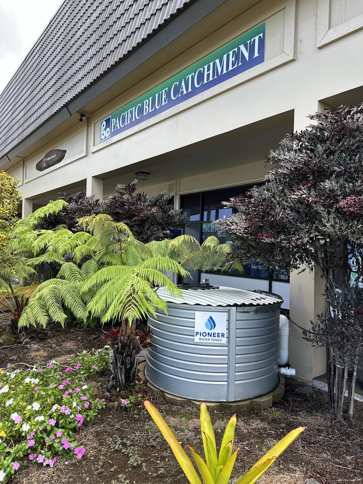Pacific Blue Catchment office signage with Pioneer water catchment tank in Captain Cook, Hawaii