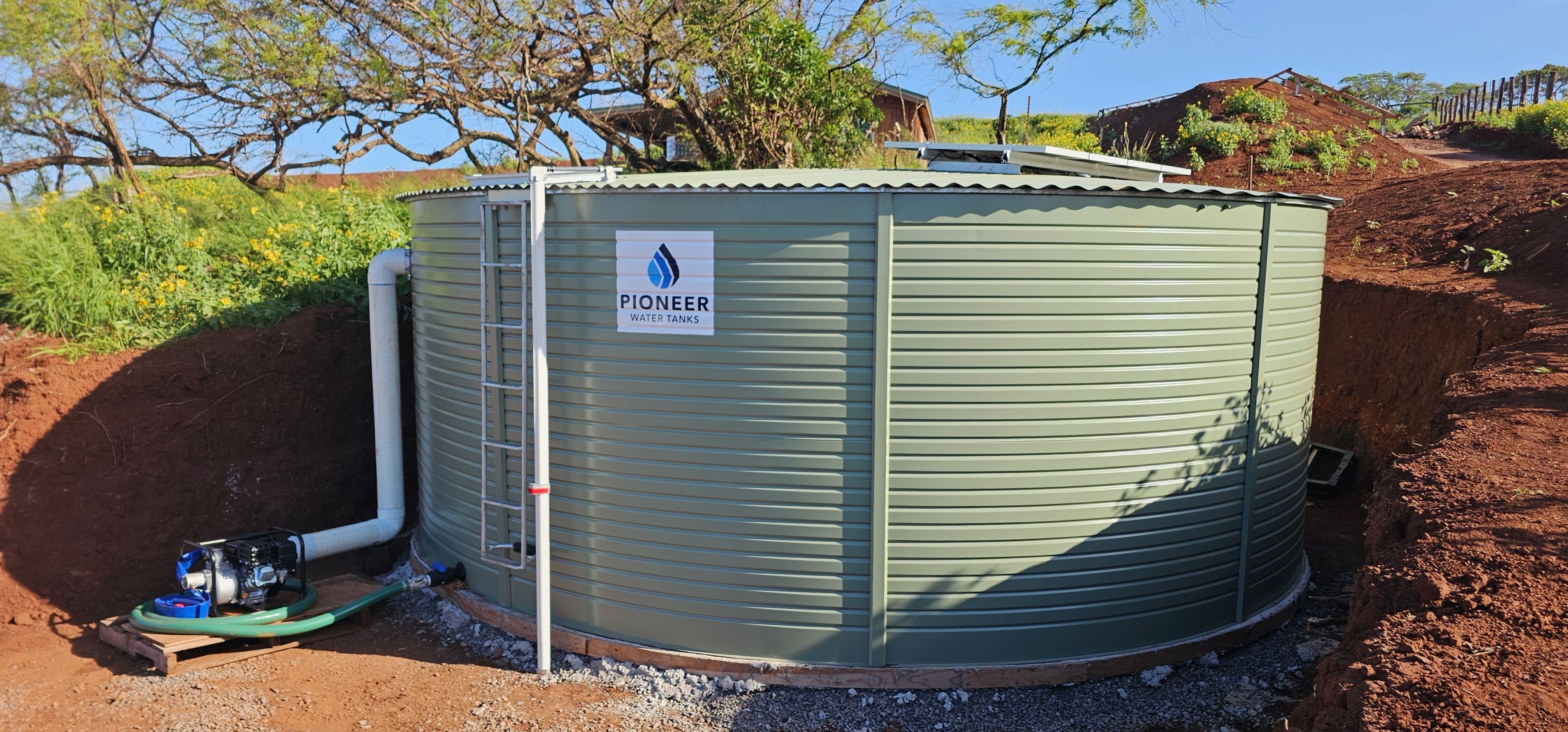 Pioneer water tank installed with pump system on red dirt Hawaii property