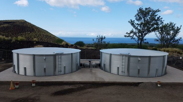 Twin galvanized Pioneer water catchment tanks installed above Kona, Hawaii with Pacific Ocean horizon